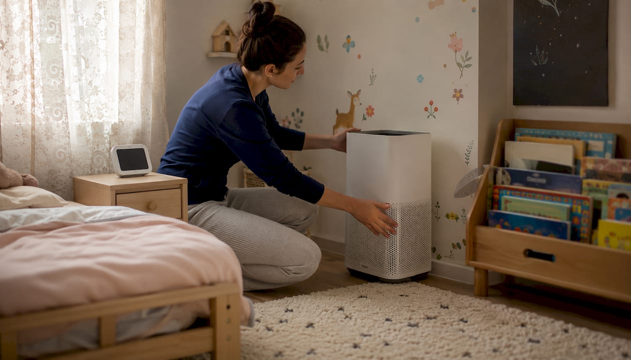 Mother adjusting air purifier in toddler's bedroom