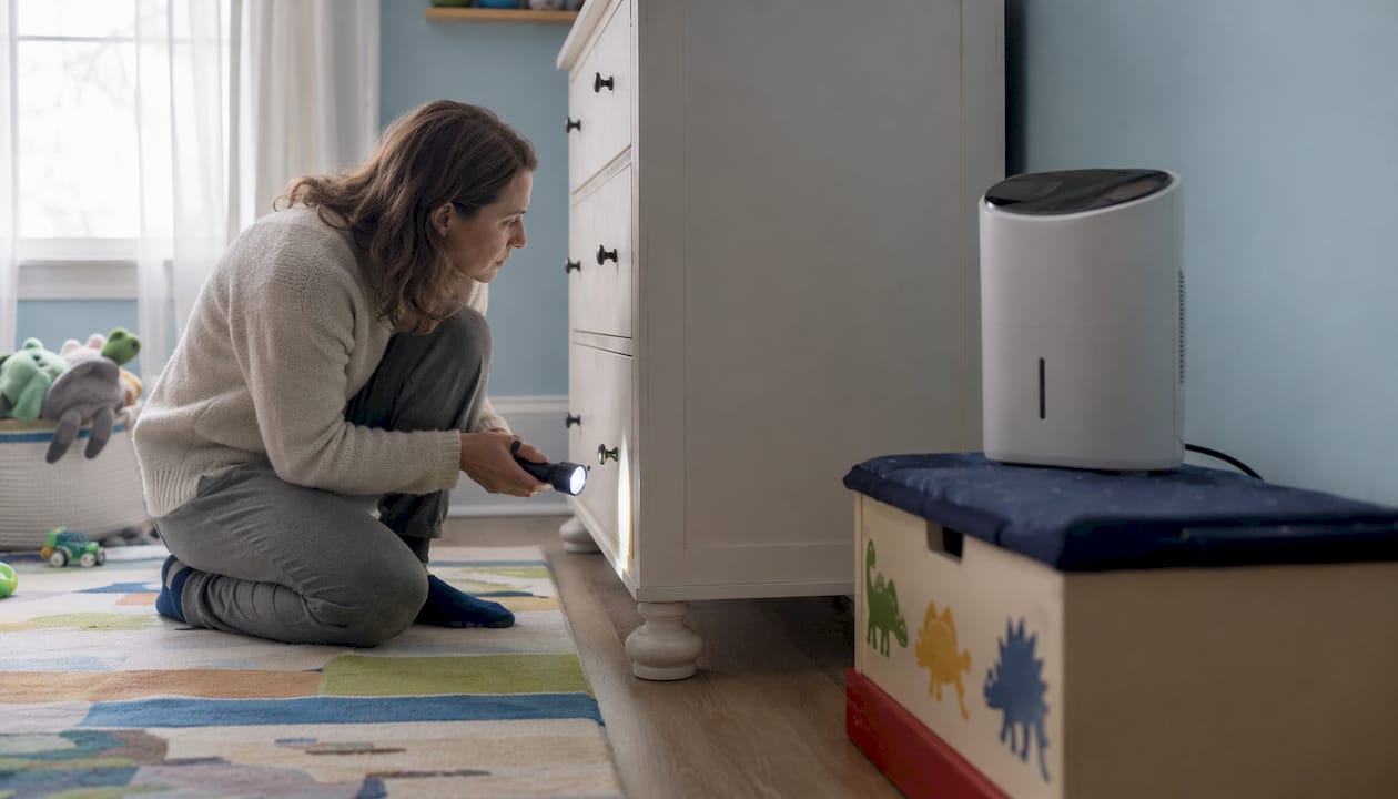 Woman inspecting behind wardrobe in child's bedroom